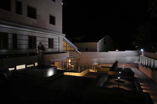 eine Person, die nachts vor einem Gebäude steht in der Unterkunft Hotel Corona in San Giovanni Rotondo