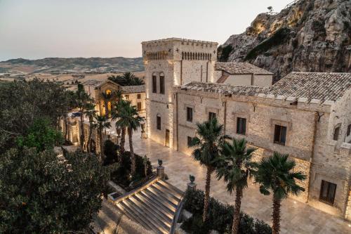 un ancien bâtiment avec des palmiers et une montagne dans l'établissement La Bouganville, à Ioppolo Giancaxio