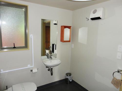 a white bathroom with a sink and a window at Bealey Avenue Motel in Christchurch