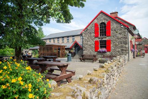 a building with red windows and picnic tables in front of it at The Garrandarragh Inn in Mullinavat