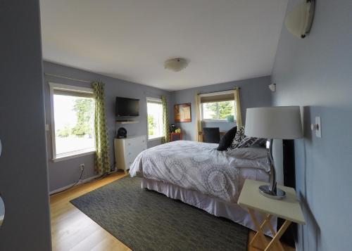 a bedroom with a bed and a table with a lamp at Money Pennies Bed and Breakfast in Campbell River