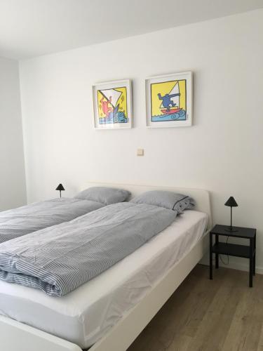 コクセッドにあるLa Bohème Koksijdeの白いベッドルーム1室(ベッド1台付)、壁に2枚の絵画が備わります。