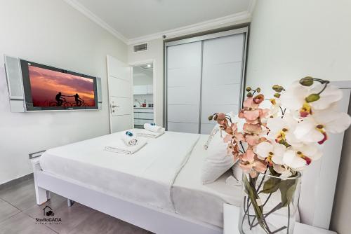 een witte kamer met een bed en een vaas met bloemen bij Turists Vacation Sea of Galilee in Tiberias