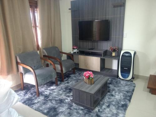 sala de estar con 2 sillas y TV en Residencial Correa Pereira, en Canela