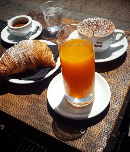 een tafel met een glas sap, croissants en een kopje koffie bij Le Stanze della Regina in Castellammare di Stabia