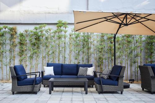 a patio with chairs and a couch and an umbrella at Kaname Inn Tatemachi in Kanazawa