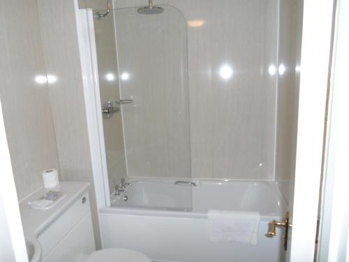 a white bathroom with a tub and a toilet at Breckland Lodge in Attleborough