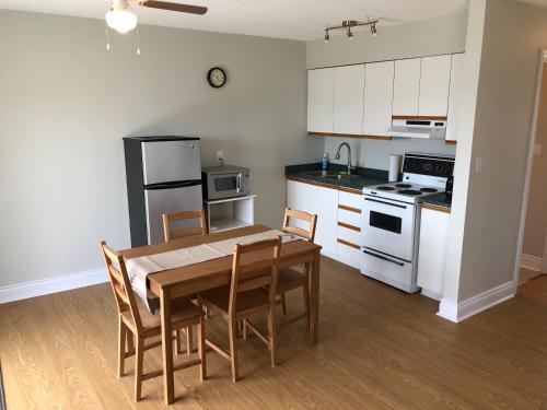 una cocina con mesa de madera y una cocina con armarios blancos. en Shores of Deer Lake en South River