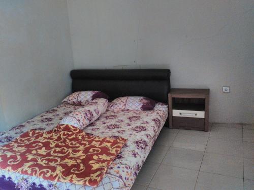 a bedroom with a bed and a night stand at Nabila Syar'i Guest House in Padalarang