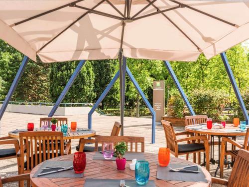 a patio with tables and chairs under a large umbrella at ibis Styles Paris Bercy in Paris