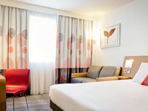 a hotel room with a bed and a chair at Novotel Lyon Gerland Musée des Confluences in Lyon