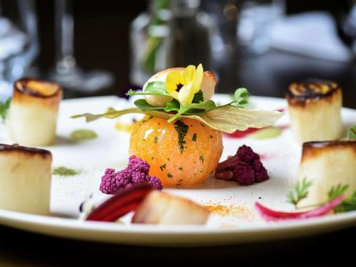 a plate of food with an orange with a flower on it at Mercure Dijon Centre Clemenceau in Dijon