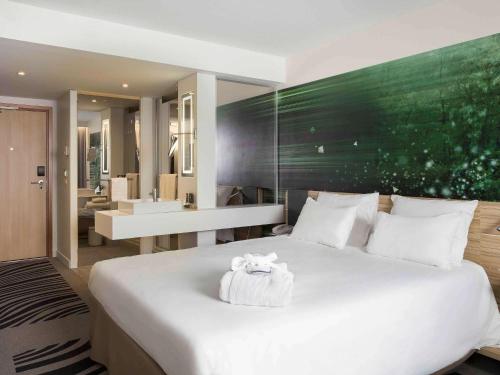 - une chambre avec un grand lit blanc et une salle de bains dans l'établissement Novotel Paris Charles de Gaulle Airport, à Roissy-en-France