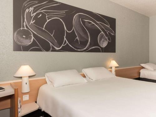 a bedroom with two beds and a painting on the wall at ibis La Bresse Gérardmer in La Bresse