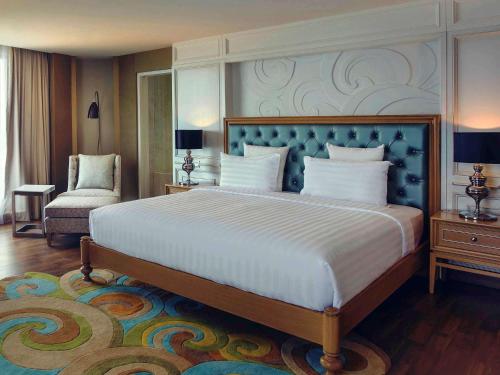 a bedroom with a large bed and a chair at Mercure Convention Center Ancol in Jakarta