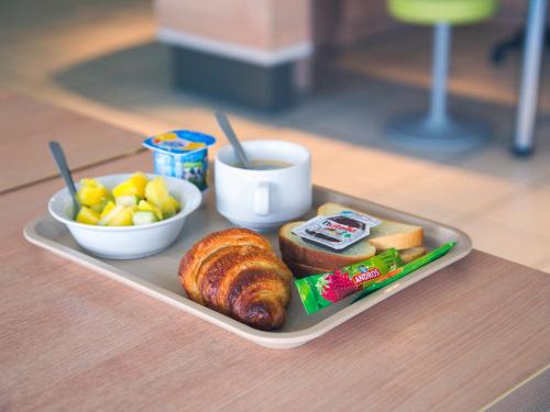a tray of food with bread and fruit on a table at ibis budget Niort - La Crèche in La Creche