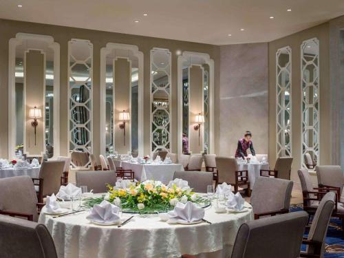 a dining room with white tables and chairs and a man at The Sebel Xining-Managed By Sofitel in Xining
