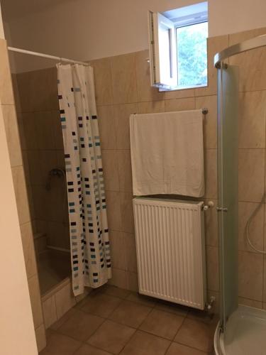 a bathroom with a shower and a towel and a window at Csini Panzió Drinkbár in Gyál