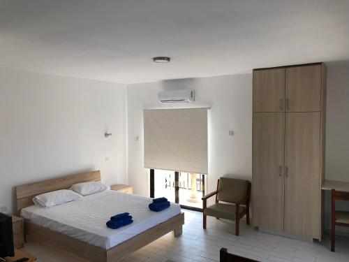 ein Schlafzimmer mit einem Bett, einem Stuhl und einem Fenster in der Unterkunft Kasapis Apts in Larnaka