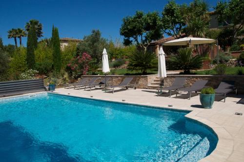 a swimming pool with chairs and umbrellas at Bastide de l'Avelan in Grimaud