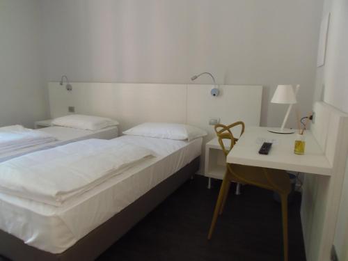 two beds in a room with a desk and a table at Albergo Dongo in Dongo