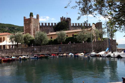 a group of boats docked in the water in front of a castle at Albergo Del Garda in Torri del Benaco