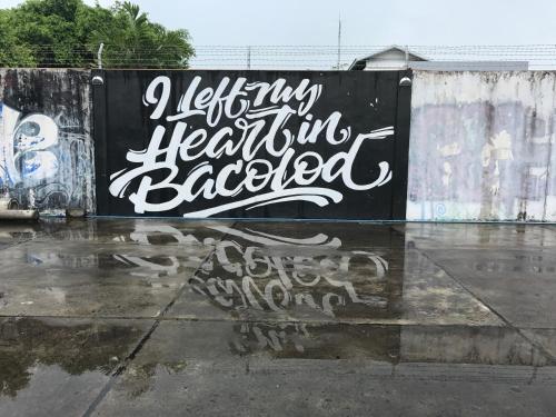 a sign on a wall with graffiti on it at Hometown Hotel - Lacson Bacolod in Bacolod