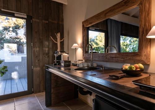 a kitchen with a counter with a sink and a mirror at Domaine Tarbouriech, Demeure & Spa in Marseillan