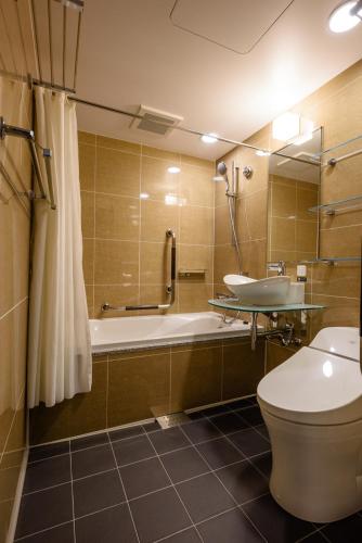 a bathroom with a tub and a toilet and a sink at APA Hotel TKP Keikyu Kawasaki Ekimae in Kawasaki
