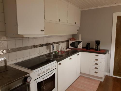 a kitchen with white cabinets and a sink and a stove at Gärdesgården Lillstugan in Maramö