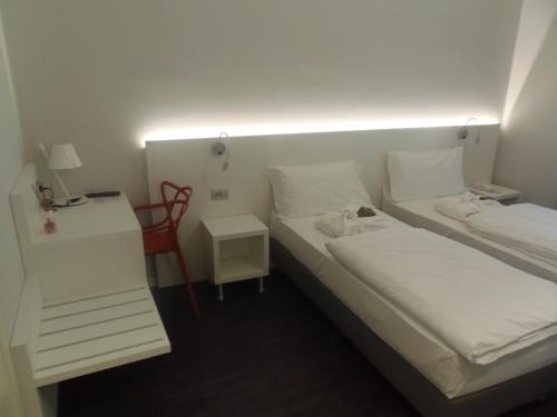 a small room with two beds and a night stand at Albergo Dongo in Dongo