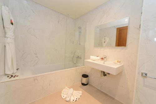 a white bathroom with a sink and a bath tub and a sink at Golden Star Casablanca in Casablanca