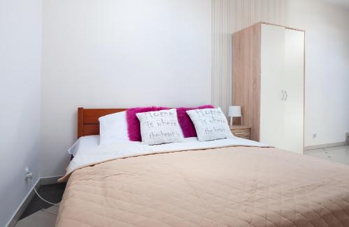 - une chambre avec un lit doté d'oreillers roses et blancs dans l'établissement PORT-ŁÓDŹ Apartment by PinPoint, à Łódź