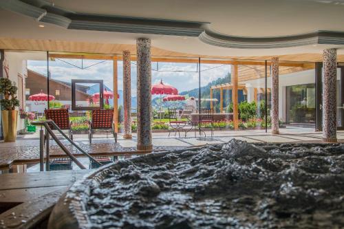 a room with a view of a patio with tables and chairs at Hotel Welponer in Selva di Val Gardena