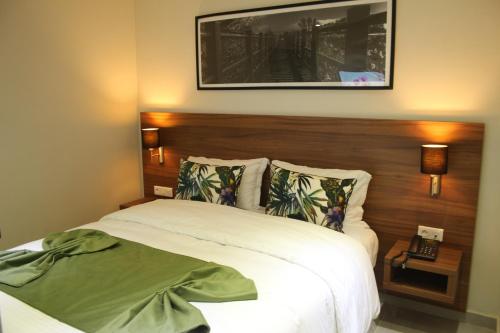 a bedroom with a white bed with a wooden headboard at L'escale Suites Résidence Hôtelière By 7AV HOTELS in Mohammedia