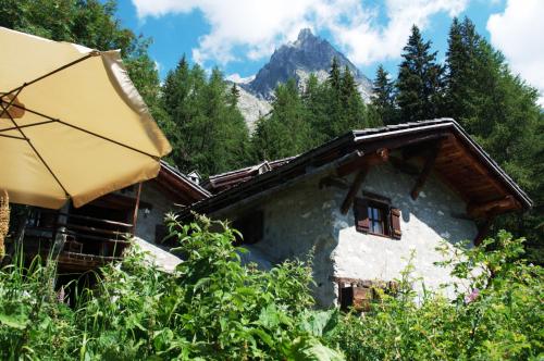 a house with an umbrella and a mountain in the background at Rochefort Valferret in Courmayeur