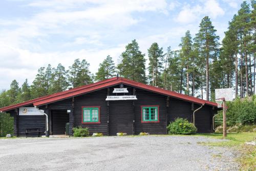 a log cabin with a red roof and green windows at Dombås Hostel in Dombås
