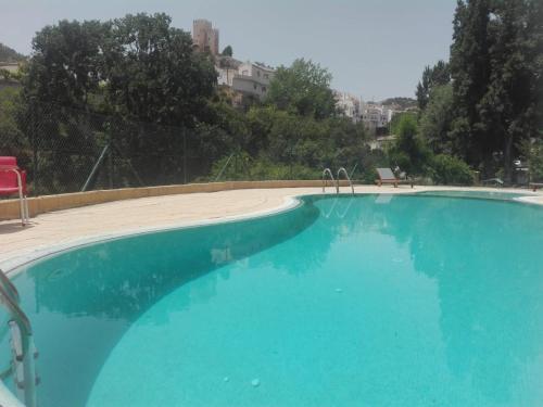 a large blue swimming pool with a red chair at AT Restaurante El Palacil in Vélez Blanco