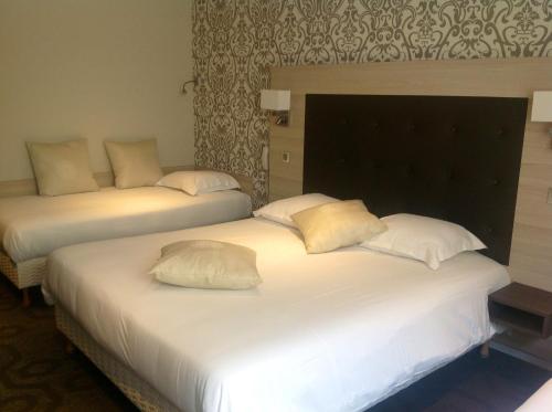 two beds with white pillows in a hotel room at Logis - Hôtel de la Baie de Somme in Le Crotoy