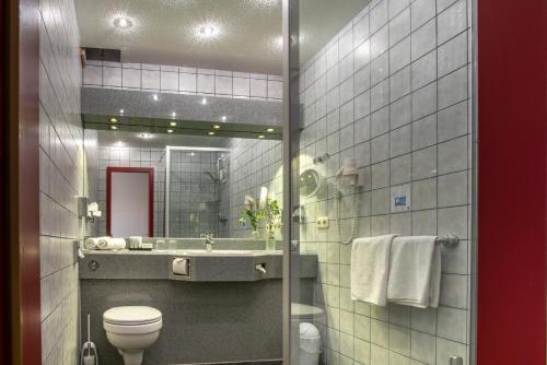 a bathroom with a toilet and a sink and a mirror at Komfort-Hotel Katerberg in Lüchow