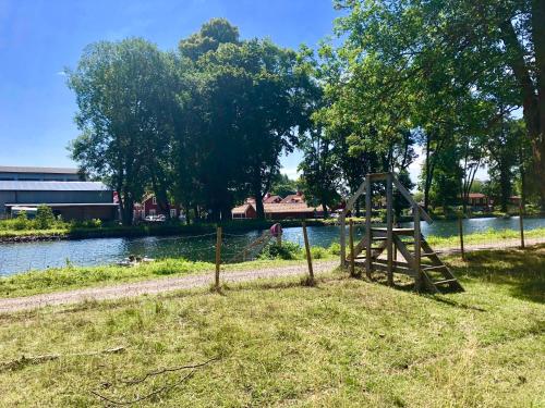 a wooden structure sitting on the grass next to a river at Liverpoolsstugan in Motala