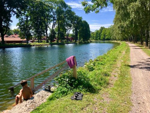 a young boy sitting on the side of a river at Liverpoolsstugan in Motala