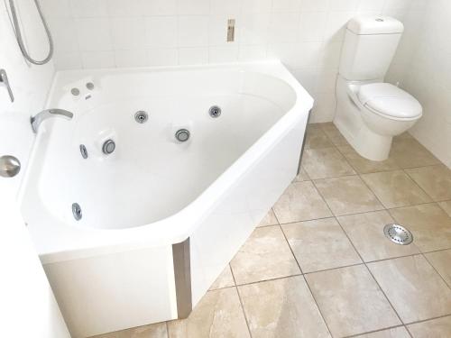 a white bath tub in a bathroom with a toilet at Avalon Manor Motel in Motueka