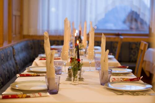 a long table with white plates and napkins and candles at Hotel Panorama in Molveno