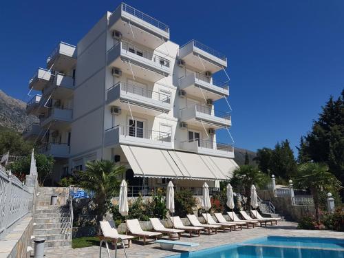 a hotel with a swimming pool and chairs and a building at Perivolos Apartments in Dhërmi