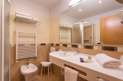 a bathroom with a sink and a toilet and a mirror at Hotel Panorama in Molveno