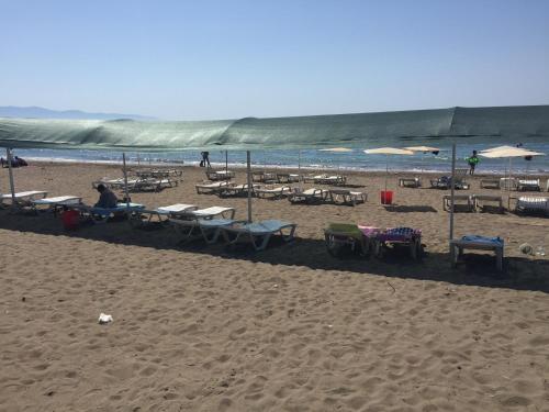 a sandy beach with tables and chairs and umbrellas at Hotel Simsek in Finike