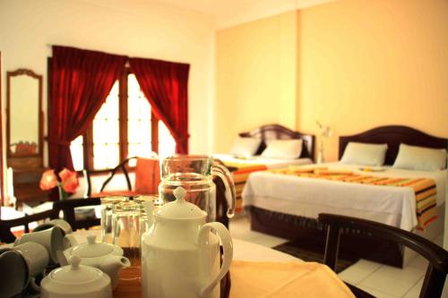 a living room with two beds and a table with cups at White Elephant Hotel in Maskeliya