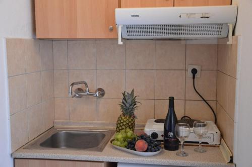 a kitchen sink with a bowl of fruit and wine glasses at Asteri's Summer in Paralia Katerinis