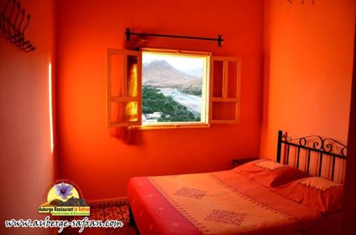 an orange bedroom with a bed and a window at Auberge Restaurant le Safran in Taliouine